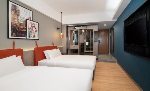 a hotel room with two beds and a flat screen tv at 利怡酒店汕头高铁站万象城店 in Ma Yu