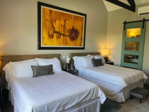 two beds in a hotel room with a painting on the wall at Boutique Hotel La Casona in Valle de Ángeles