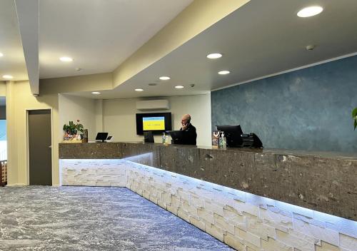 a man sitting at a reception desk in a lobby at Sudima Hotel Lake Rotorua in Rotorua