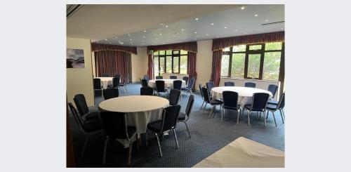 a conference room with tables and chairs and windows at Passage House Hotel in Newton Abbot