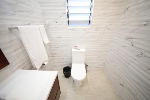 a white bathroom with a toilet and a sink at First home Fiji in Nadi