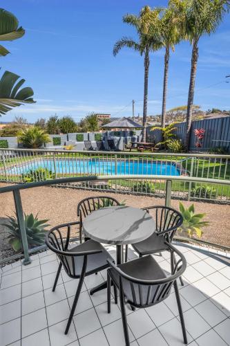 a patio with a table and two chairs and a pool at The Palms Apartments in Merimbula