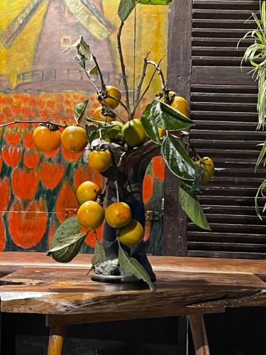 a vase filled with fruit on top of a wooden table at Redhouse Dalat Hotel in Da Lat