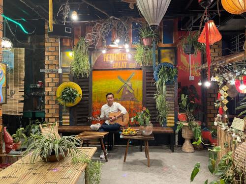 a man sitting on a bench playing a guitar at Redhouse Dalat Hotel in Da Lat