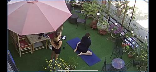 a woman is standing under an umbrella in a garden at Redhouse Dalat Hotel in Da Lat