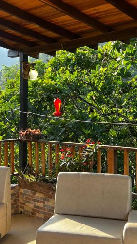 a couch on a porch with a red vase in a tree at Hostal Los Wichos in Minca