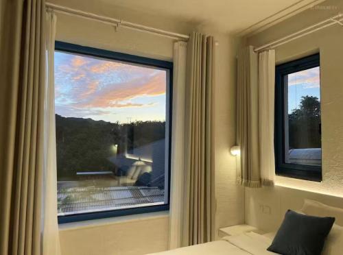 a bedroom with a window with a view of the sunset at 北京怀柔方糖民宿 in Sanduhe