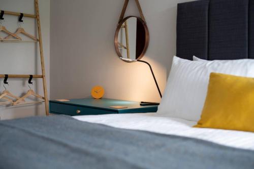 a bed with a yellow pillow and a table with a lamp at Cosy Nook in Windermere
