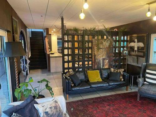 a living room with a couch and a table at Electric Waihi Beach House - family & dog friendly, close to beach, pool table, outdoor fire room, skate ramp in Bowentown