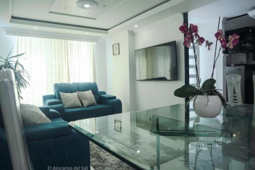 a living room with a blue couch and a glass table at El Descanso del Sol in Sogamoso