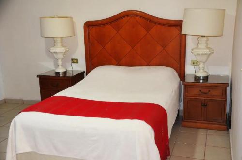 a bedroom with a bed with a red and white blanket at Hotel Boutique Los Arcos in Los Mochis