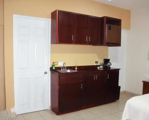a kitchen with brown cabinets and a sink at Hotel Boutique Los Arcos in Los Mochis