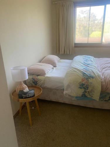 a bedroom with a bed and a table with a lamp at Elegant Castlehill Stay in Castle Hill