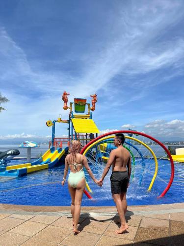 a man and a woman holding hands at a water park at Crusoe Cabins Costa Azalea in Davao City