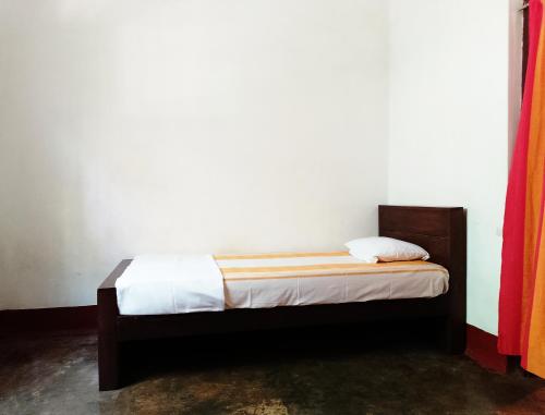a bed in a room with a white wall at Olukaranda Walauwa in Kekirawa