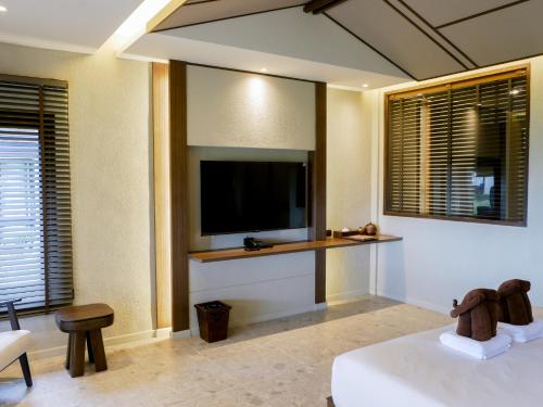 a bedroom with a flat screen tv and a bed at Ayara Villas - SHA Extra Plus in Khao Lak