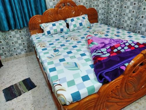 Una cama de madera con una manta a cuadros encima. en Diya Homestay, en Santiniketan