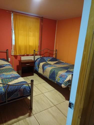 a bedroom with two beds and a yellow curtain at Hostal Vista al Mar in Puerto Natales