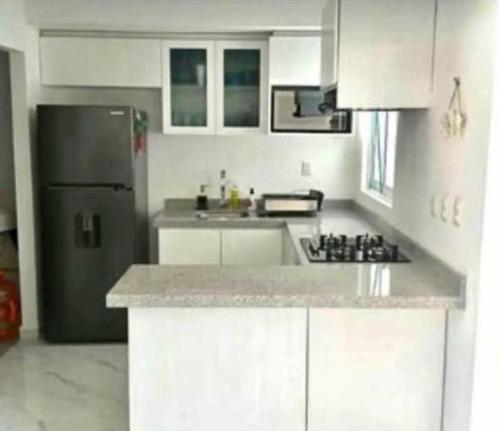 a kitchen with white cabinets and a stainless steel refrigerator at Casa real del palmar in La Sabana