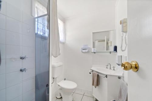 a white bathroom with a toilet and a sink at Tally Ho Motor Inn in Tenterfield