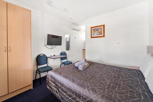 a bedroom with a bed and a table and chairs at Tally Ho Motor Inn in Tenterfield