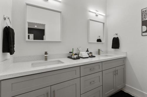 a white bathroom with two sinks and two mirrors at Stylish 3 Bedroom Rental - Just Minutes from Dowtown Houston in Houston