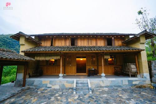 a large wooden house with a patio in front of it at Pachidua Ecolodge - Homestay Du Già in Làng Cac
