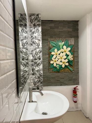 a bathroom sink with a painting of a flower on the wall at Jomtien Beach Hostel - Soi 7 Prime Spot - 200m to Beach next to Food Market in Jomtien Beach