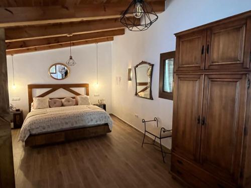 a bedroom with a bed and a large wooden cabinet at Loft Rural El Pajar del Molino in Benamahoma