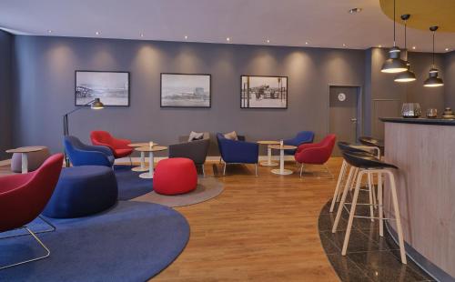 a waiting room with colorful chairs and tables at Holiday Inn Express Frankfurt Airport by IHG in Mörfelden-Walldorf