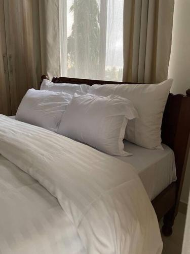 a white bed with white pillows and a window at One bedroom in Bamburi in Mombasa