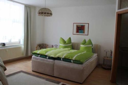 a bedroom with a bed with green pillows on it at City-Apartment "royshell" in Güstrow