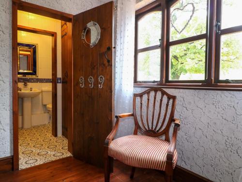 a bathroom with a chair and a sink and a mirror at Woodpit Cottage in Nottingham