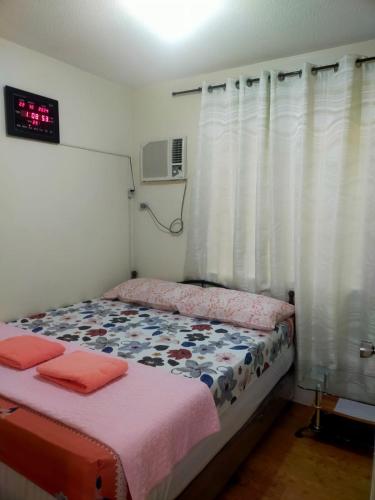 a bedroom with a bed and a clock on the wall at Two-Bedroom at San Remo Oasis in Cebu City