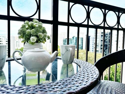a table with a tea pot and a vase of flowers at Free carpark, balcony with park views, pool and spa in Auckland