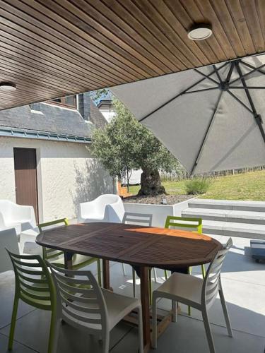 une table et des chaises en bois sur une terrasse dans l'établissement La Villa des Ajoncs, accès privé à la plage, à Carnac