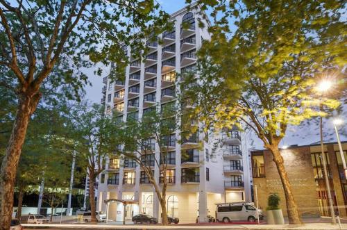 a white building with trees in front of it at Free carpark, balcony with park views, pool and spa in Auckland
