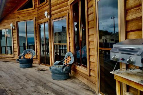 a porch of a wooden cabin with two chairs and a grill at Cabaña del árbol in Pachuca de Soto