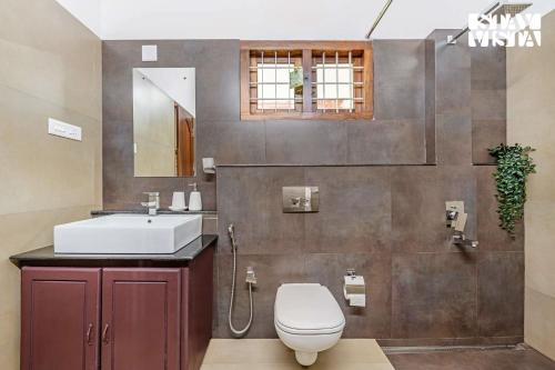 a bathroom with a toilet and a sink and a mirror at StayVista at Wellbeing Villa in Wayanad