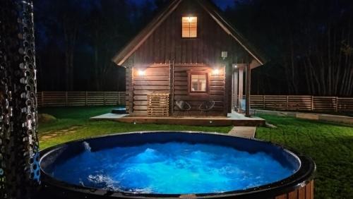 a hot tub in front of a log cabin at night at Jäägri Saunamaja in Parksi