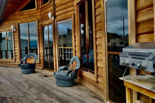 a porch of a wooden cabin with two chairs and a grill at Casa del árbol in Pachuca de Soto