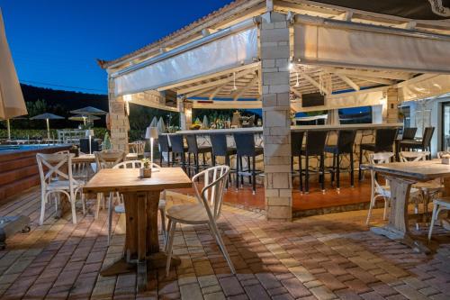 a patio with tables and chairs and a bar at Nikos Apartments in Stalida