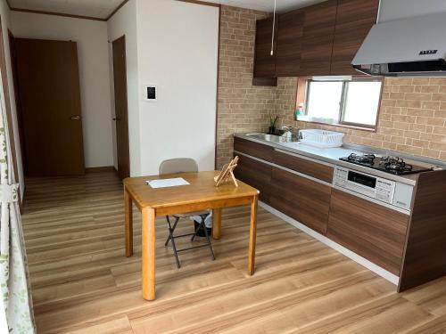 a kitchen with a wooden table and a wooden floor at ラフォーレハウス in Hitoyoshi