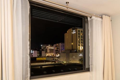 a window with a view of a city at night at La Belle Luxury Suite Windhoek City Centre in Windhoek