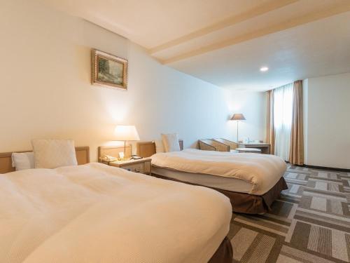 a hotel room with two beds and a window at Hotel New Century in Okinawa City
