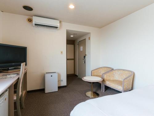 a room with a bed and a desk and a tv at Hotel New Century in Okinawa City