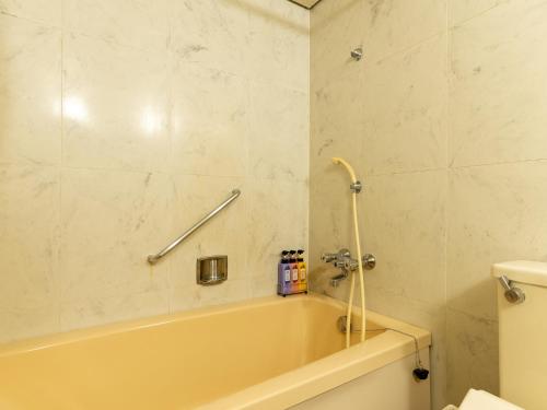 a bathroom with a tub and a toilet at Hotel New Century in Okinawa City