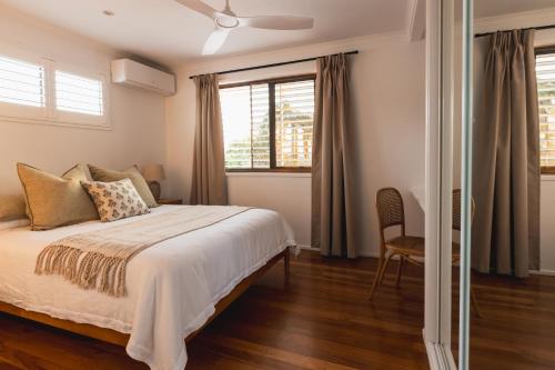 a bedroom with a bed and a chair and windows at Noosa Gem in Peregian Beach - Ocean View - Steps to beach & village! Dog and family friendly in Peregian Beach