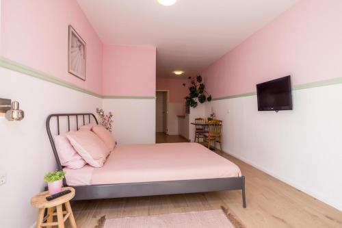 a bedroom with pink walls and a bed with pink pillows at Bed & Stay Kersenbloesem in Nijswiller
