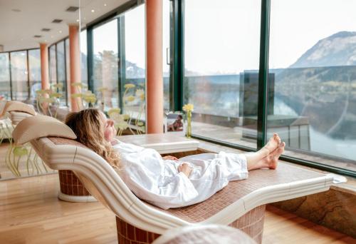 a woman laying in a chair looking out of a window at Grand Hotel Zell am See in Zell am See